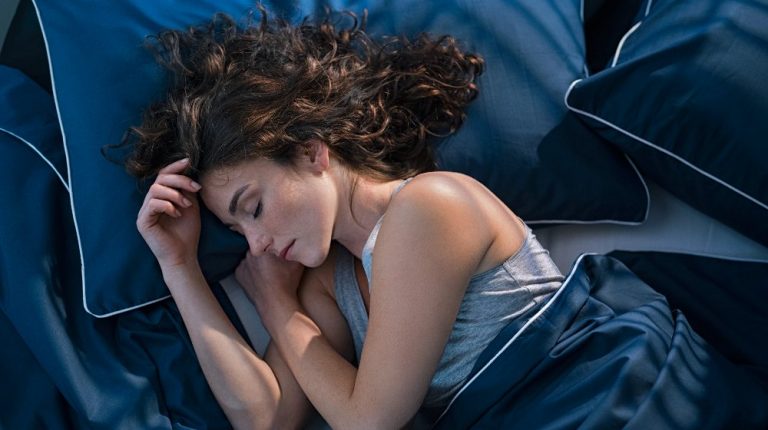 young woman sleeping on side in her bed at night | The Use of 'Cold' Tech to Improve Your Deep Sleep