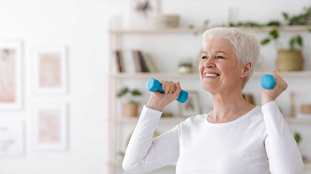 Smiling-Senior-Lady-Exercising-With-Dumbbells-At-Home | feature | 3 Proven Ways To Reverse Biological Age By Three Years