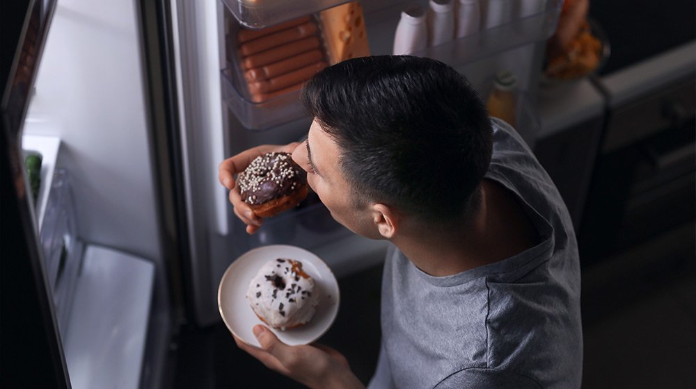 Young-man-eating-food-near-refrigerator-at-night-Impact-of-Intermittent-Fasting-on-Sleep