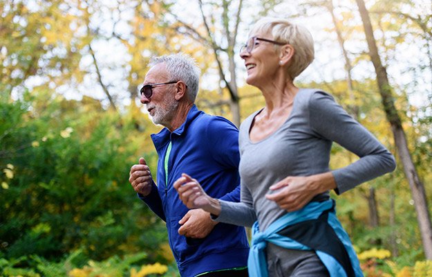Cheerful-active-senior-couple-jogging-in-the-park.-Exercise-together-to-stop-aging-The-Benefits-and-Risks-of-Reversing-Aging